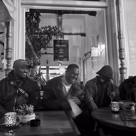 Pious, en bob, avec des amis à une table de café le soir, des bougies sur les tables.