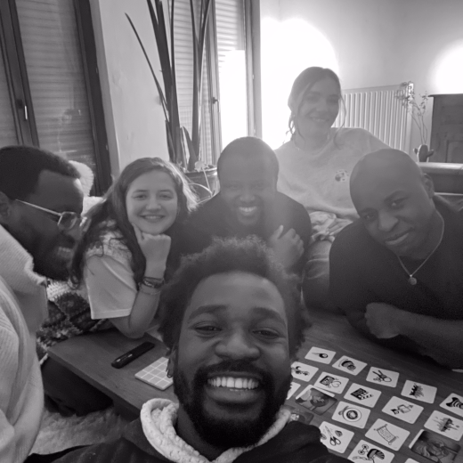 Le selfie d'un ami pendant une soirée de jeux de cartes ; Pious est juste derrière lui, avec d'autres amis autour de la table.